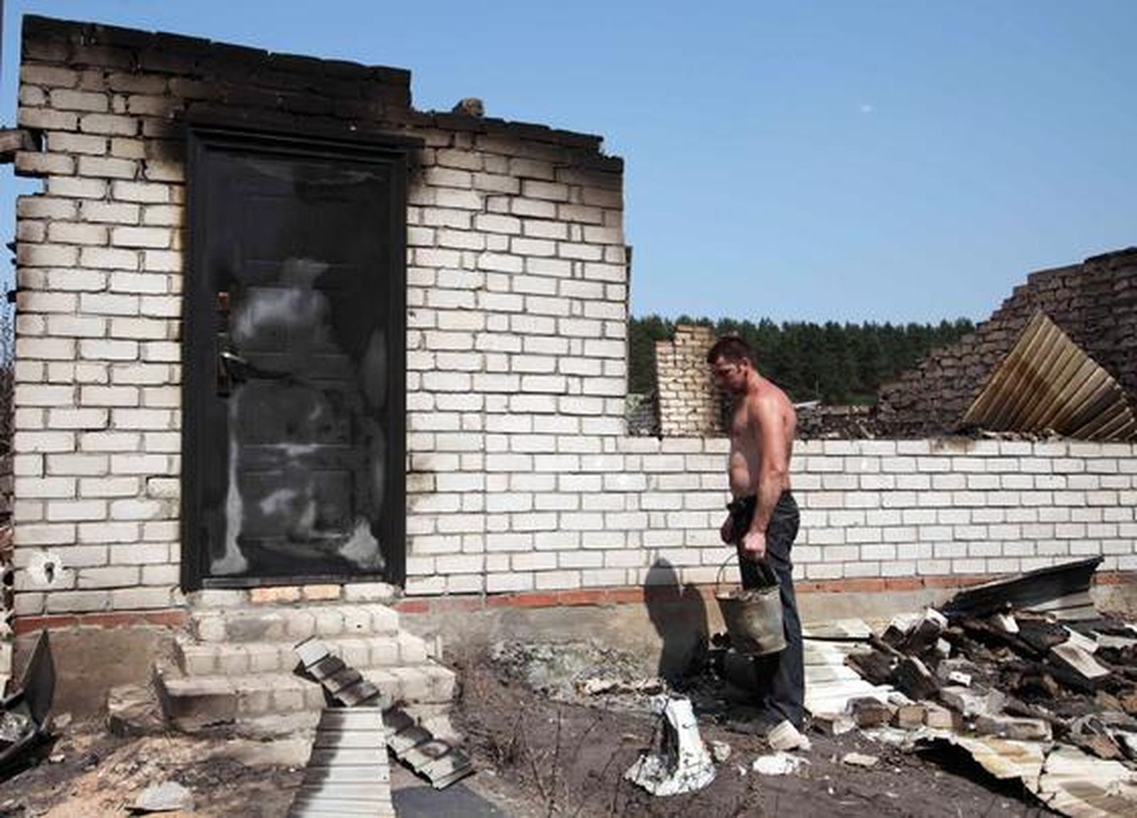 Un hombre mira su casa arrasada por las llamas. / AFP