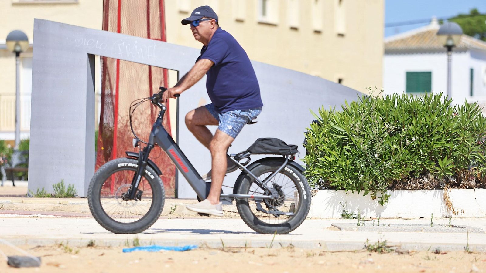 Un hombre en bicicleta bajo el sol de junio en Punta Umbría.