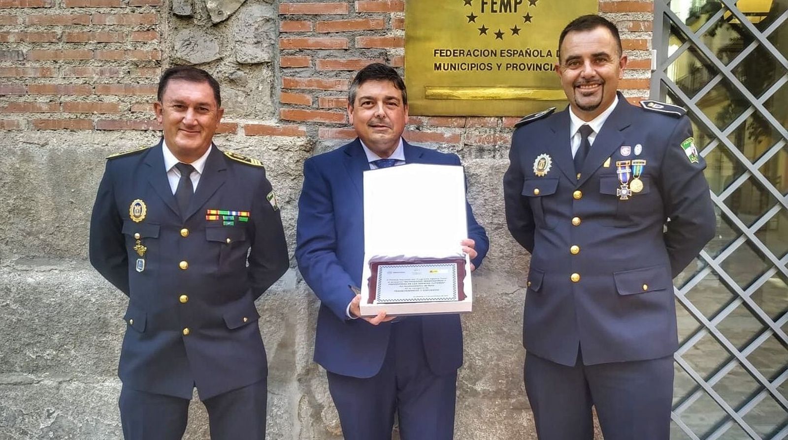 El primer teniente de alcalde, Daniel Manrique de Lara, mostrando el galardón en Madrid junto al inspector jefe de la Policía Local, Manuel Muñoz, y el agente tutor Juan José Paredes.