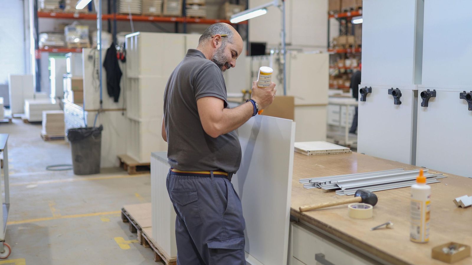 Un empleado de BC3 Cocinas usa pegamento para unir madera