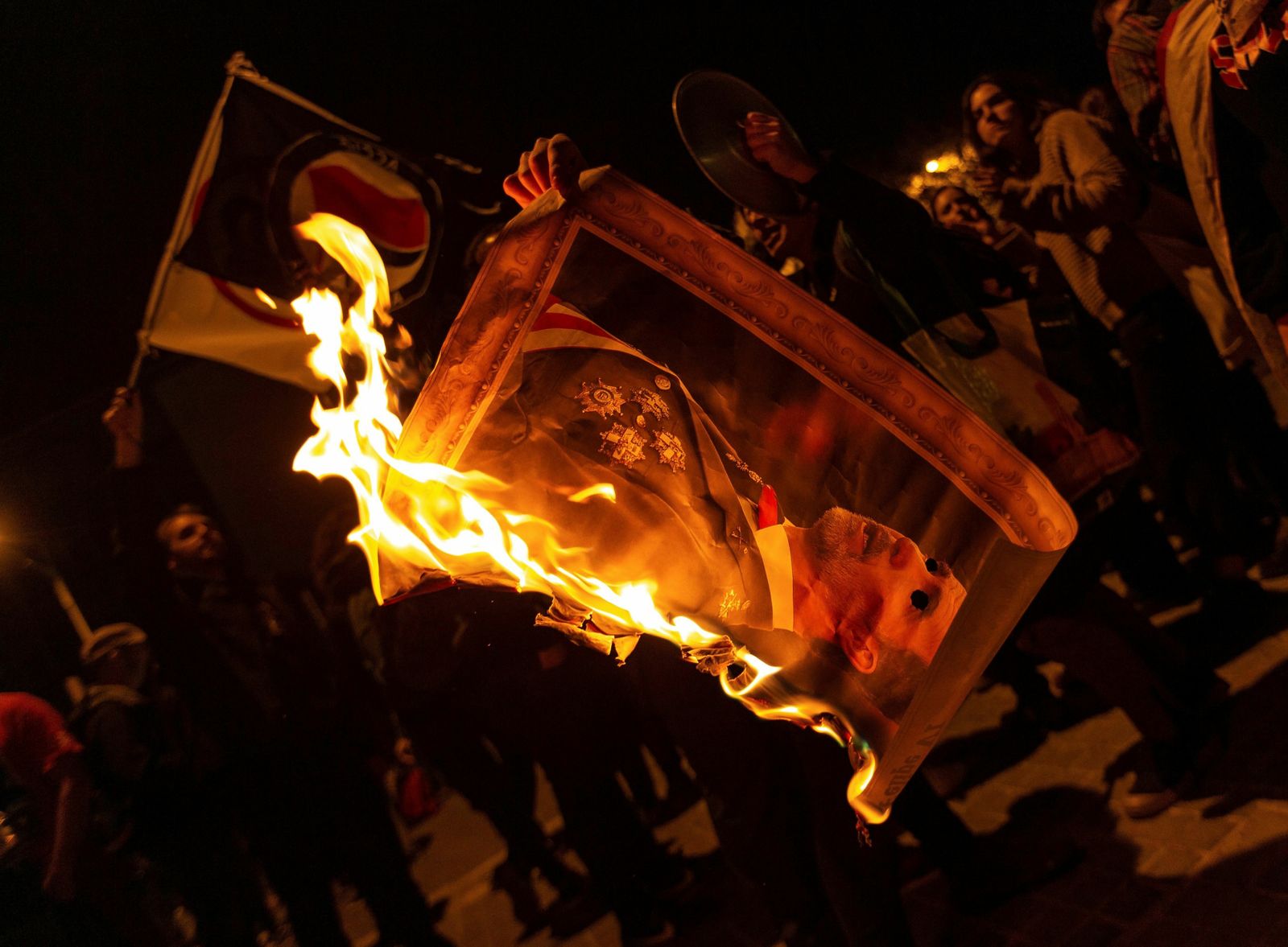 Varios manifestantes quemando fotos del rey Felipe VI durante la protesta esta noche en la avenida Diagonal de Barcelona.
