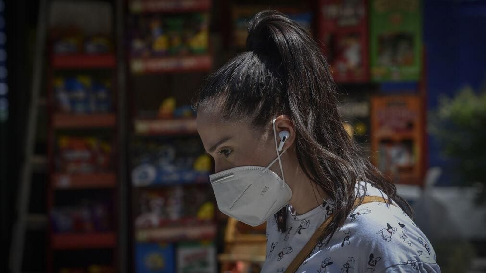 Una joven pasea con mascarilla por la calle.