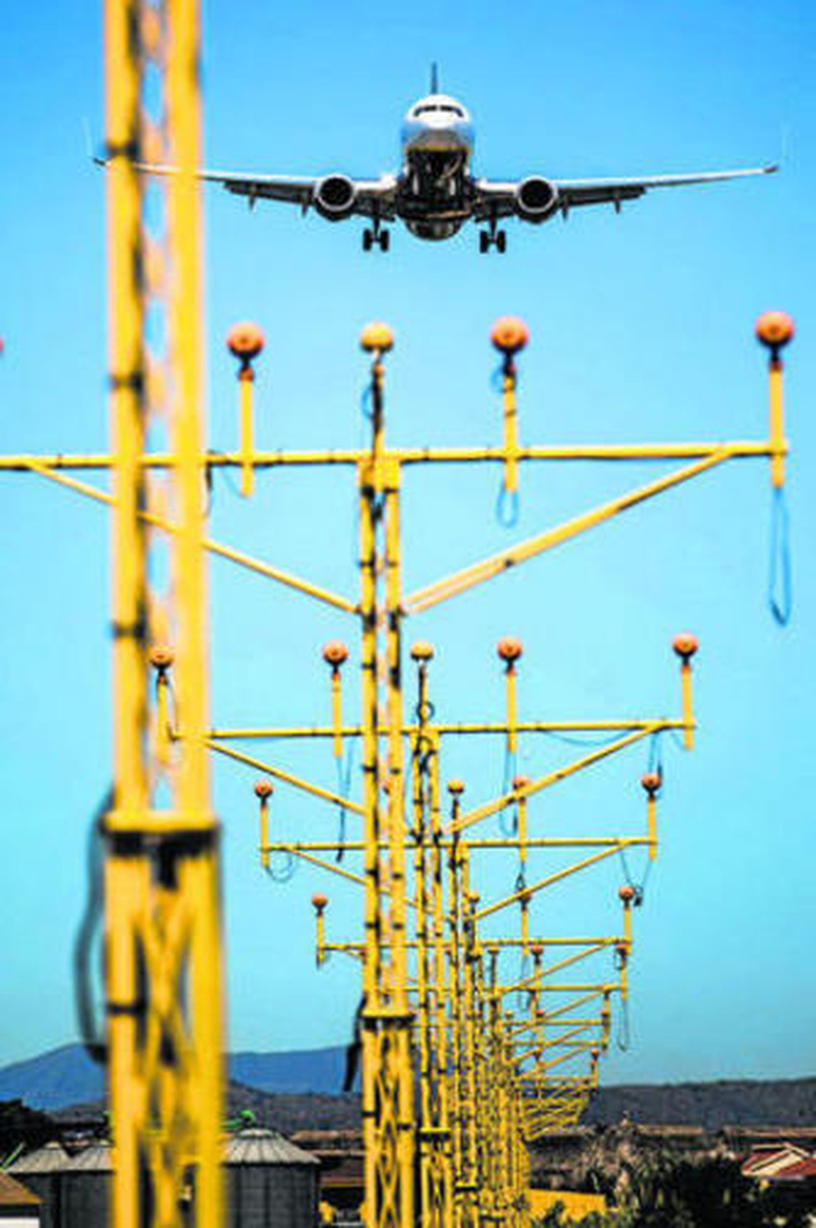 Primer plano las antenas del sistema GBAS con un avión aterrizando.