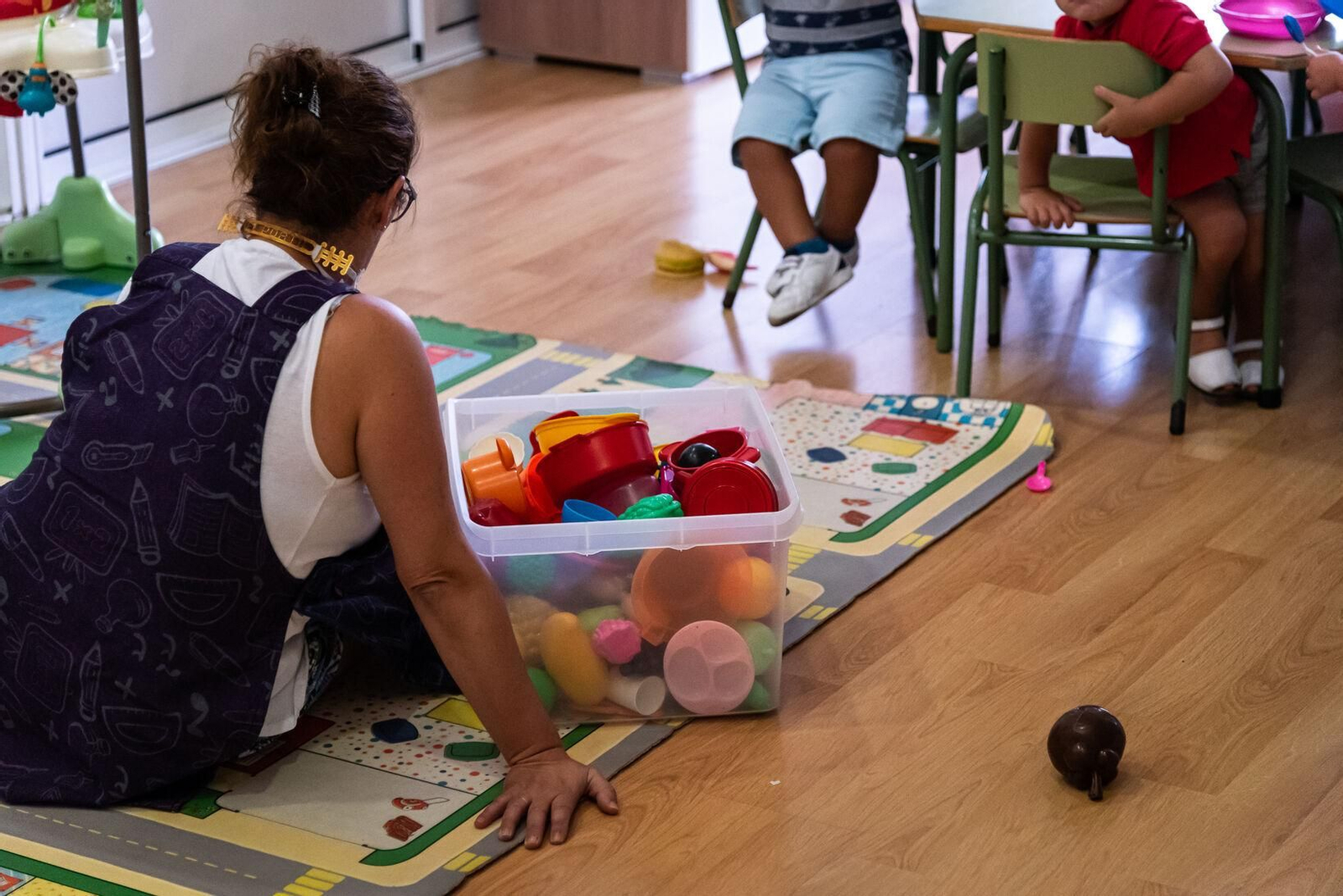 Una monitora recoge los juguetes en una escuela infantil.