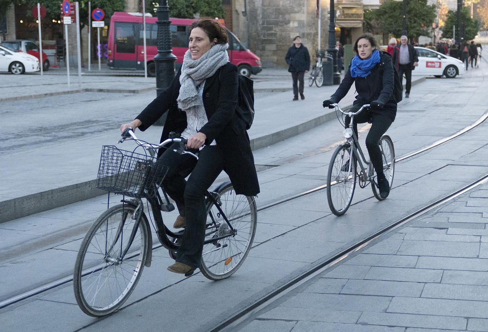 Dos ciclistas abrigadas con bufandas cruzan la Avenida de la Constitución.