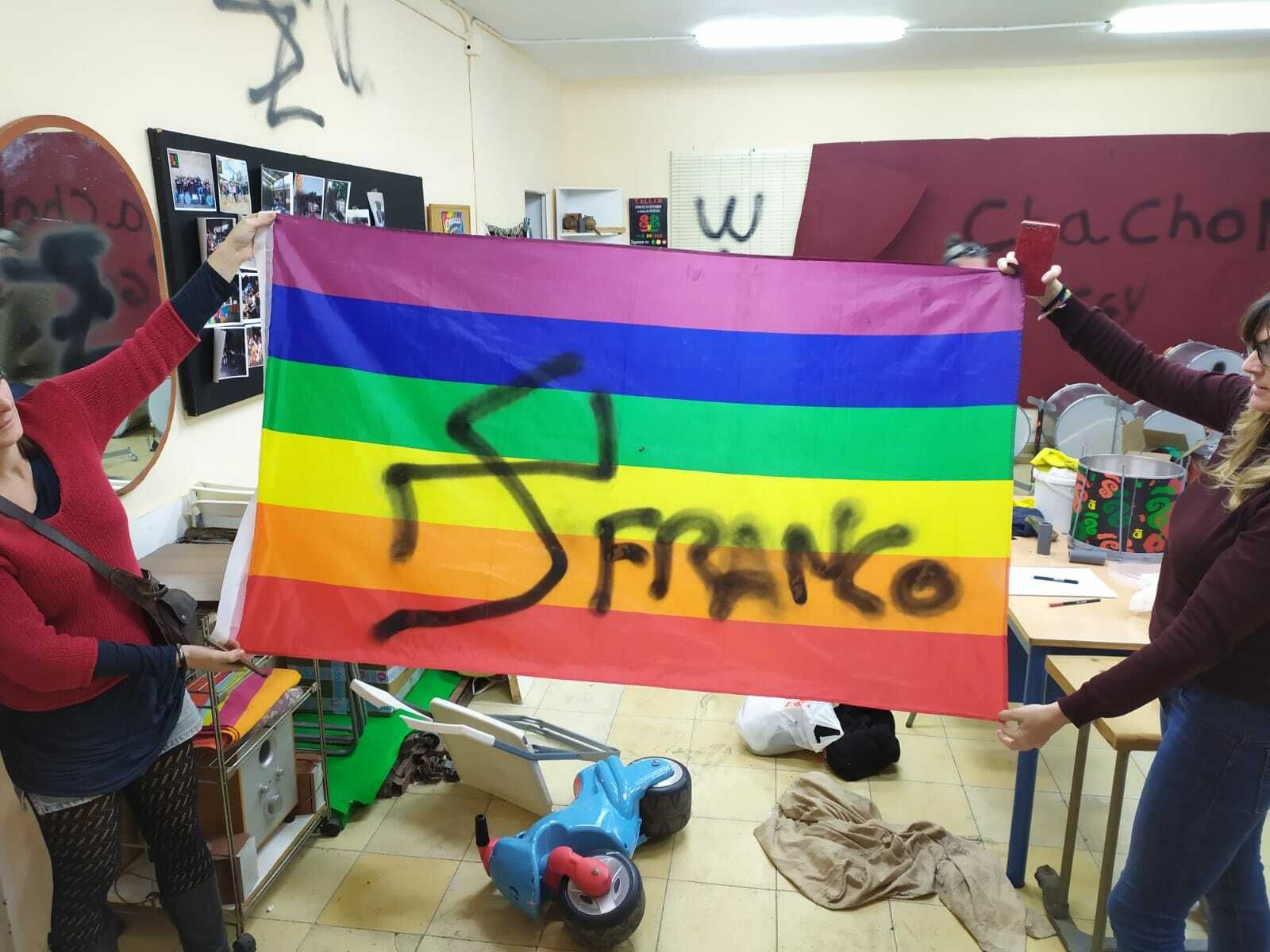 Dos componentes de Yemú Yembá muestran una de las pintadas en una bandera.