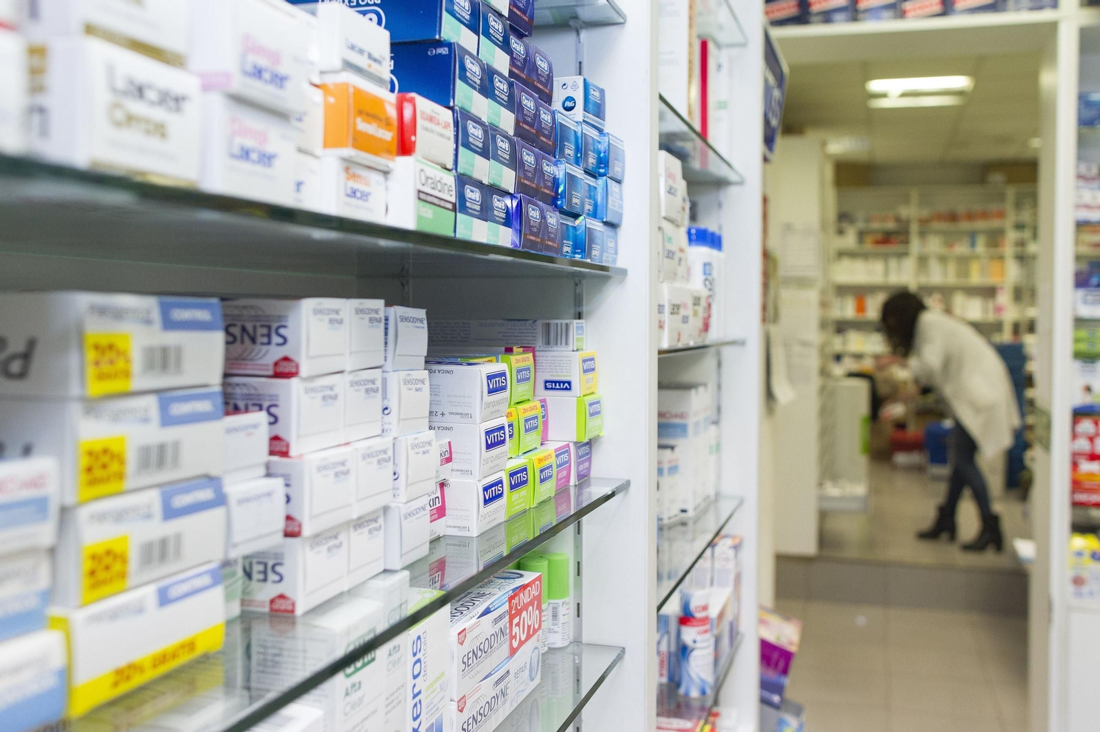 Una farmacéutica busca medicamentos en su botica.