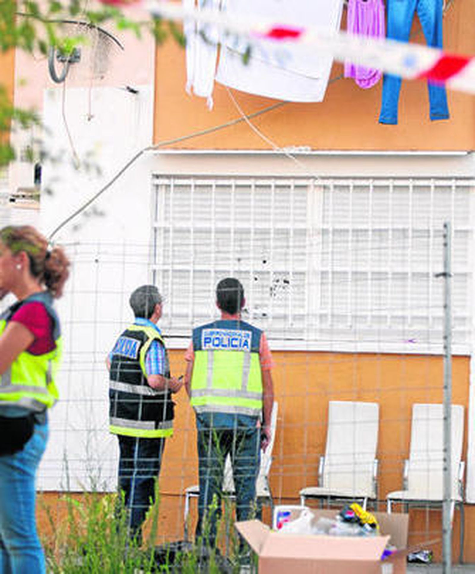 Varios policías examinan los impactos en la persiana de una de las viviendas tiroteadas en las Tres Mil Viviendas.