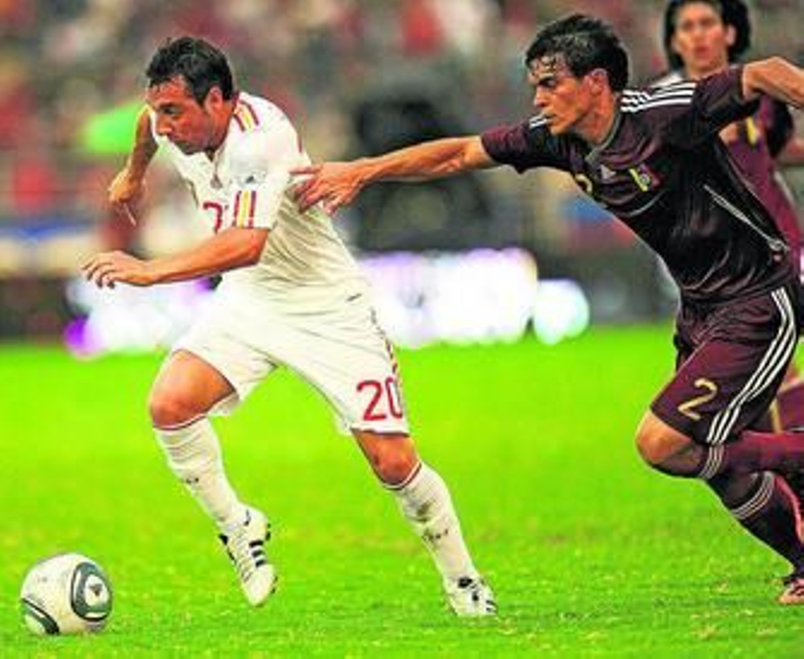 El venezolano Di Giorgi intenta sujetar a Cazorla, en el partido que les enfrentó ante España.