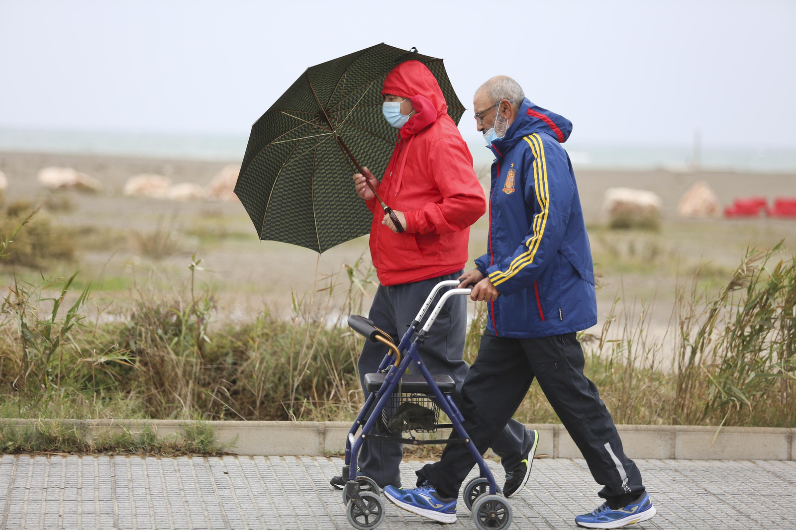 Dos personas, en el paseo marítmo de Huelin, se protegen de la lluvia.