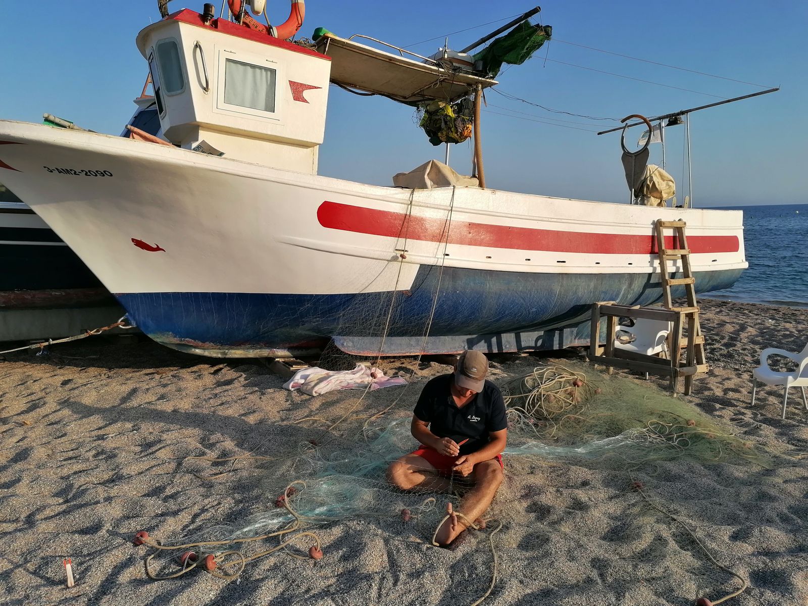 Luis 'El Chato' hijo cose las redes de pesca.