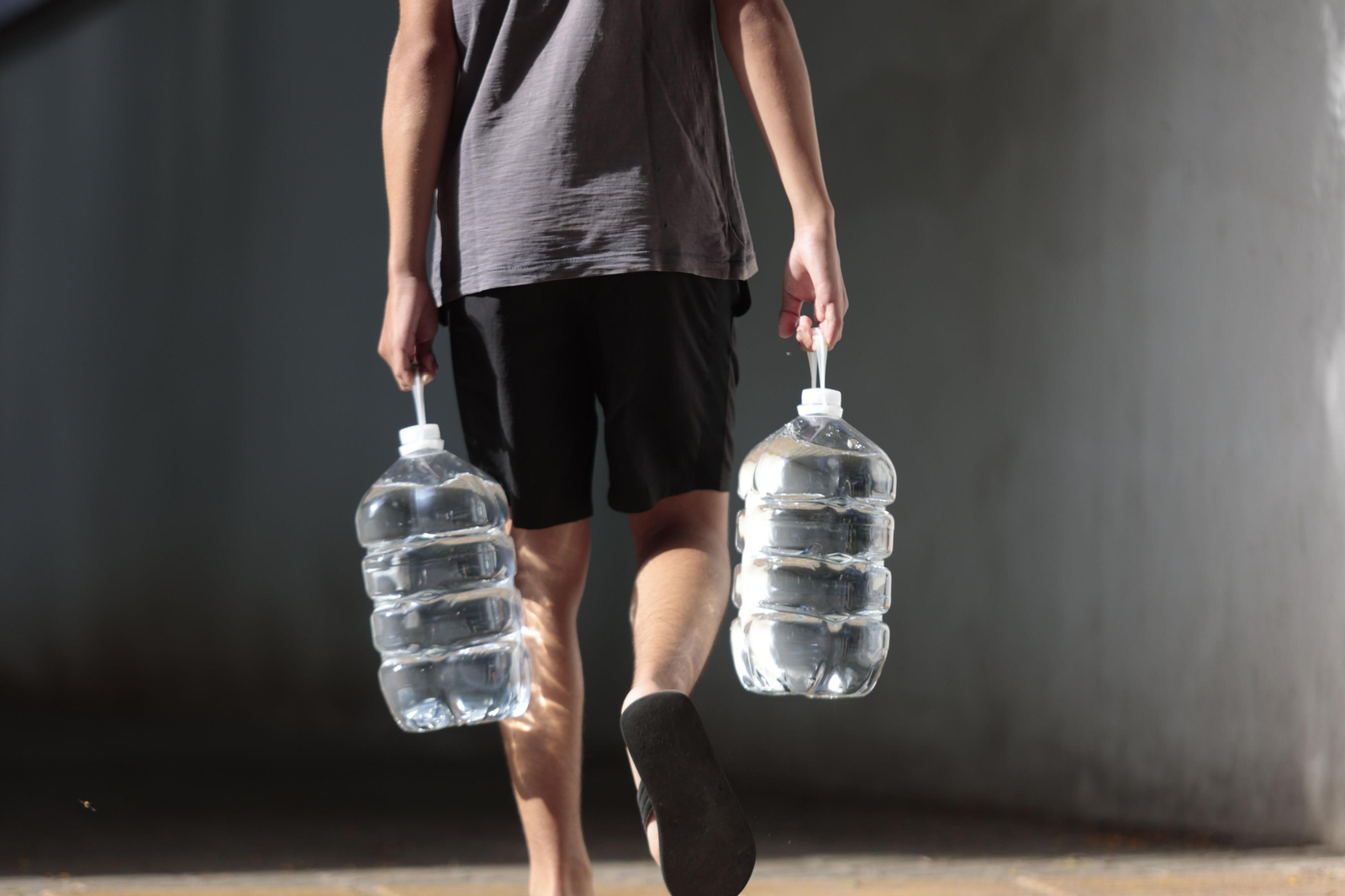 Un hombre portando dos garrafas de agua.
