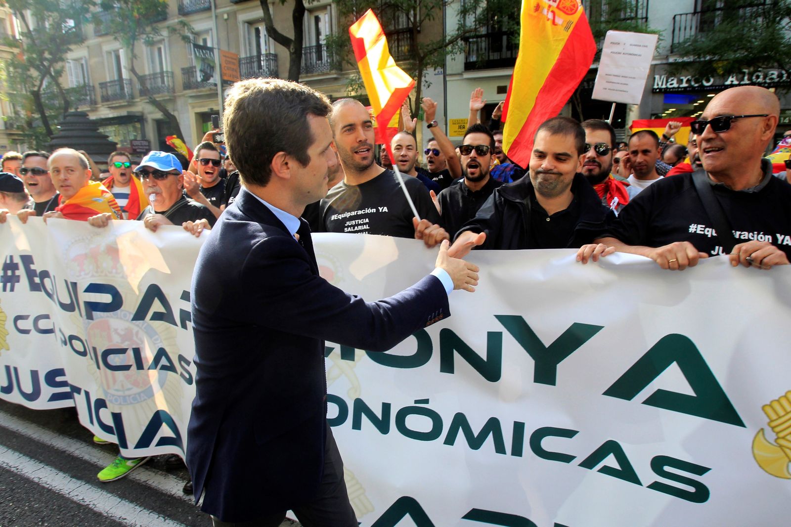 El vicesecretario general de Comunicación del PP, Pablo Casado, saluda a los participantes en la concentración convocada ayer por Jusapol frente a la sede del PP en la madrileña calle Génova.
