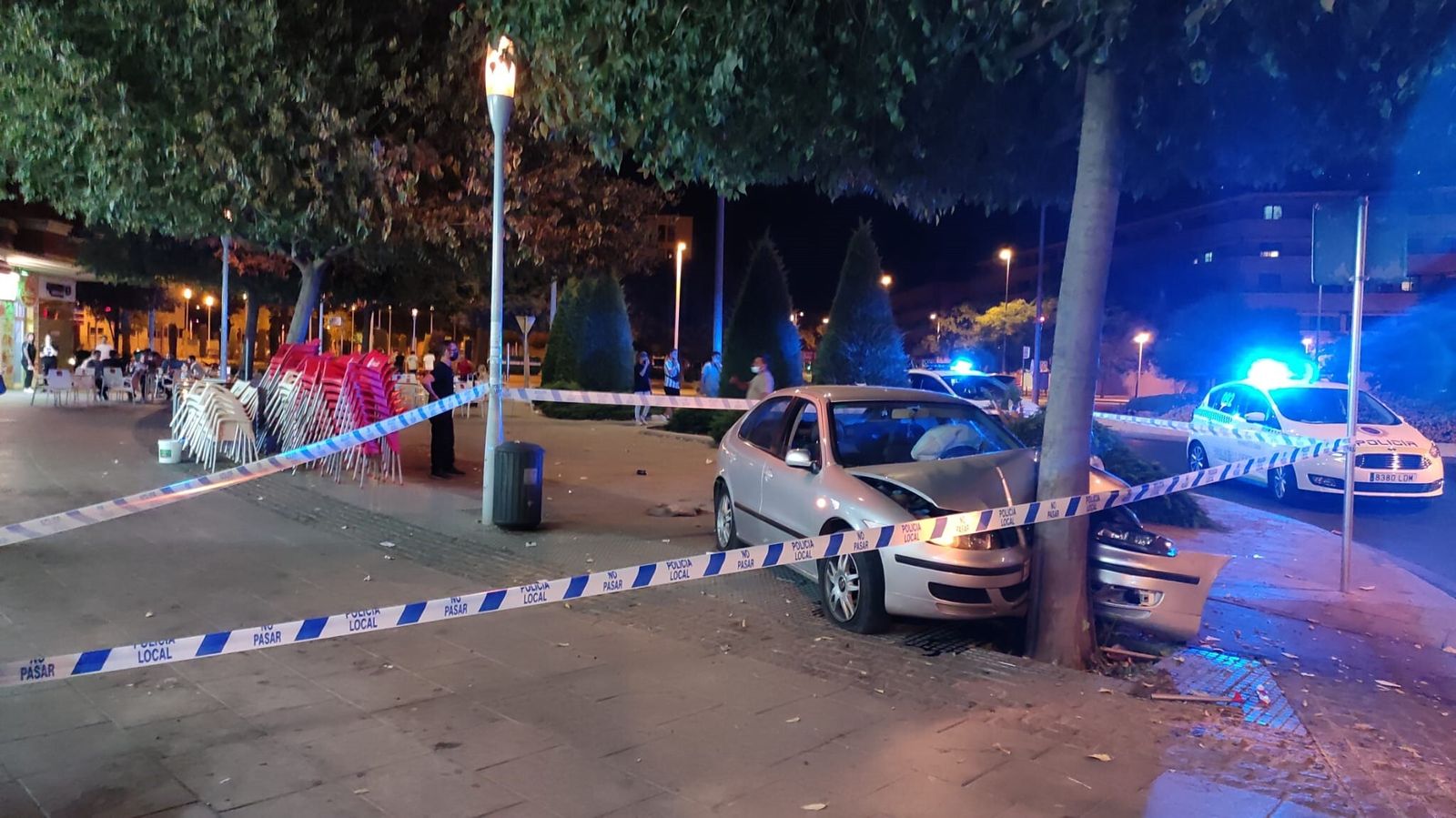 El coche, tras arrollar las mesas de una terraza y chocar contra un árbol.