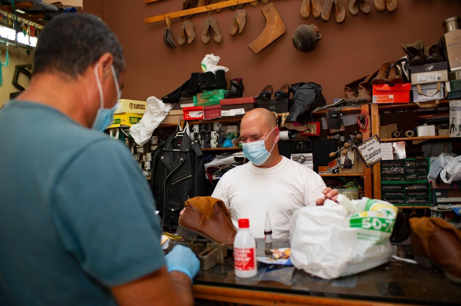 Un cliente entrega unos zapatos en en establecimiento de reparación de calzado