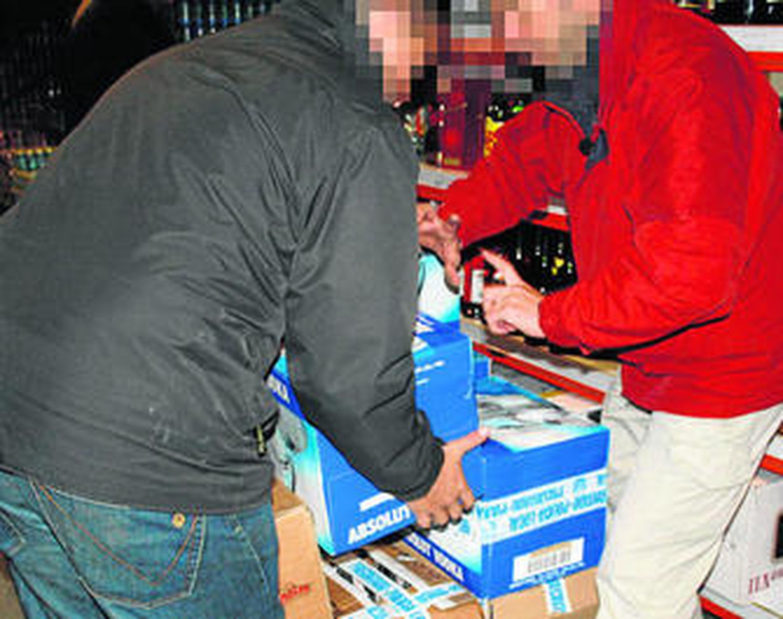 Dos agentes de la Policía Local inmovilizan varias cajas con botellas de alcohol.