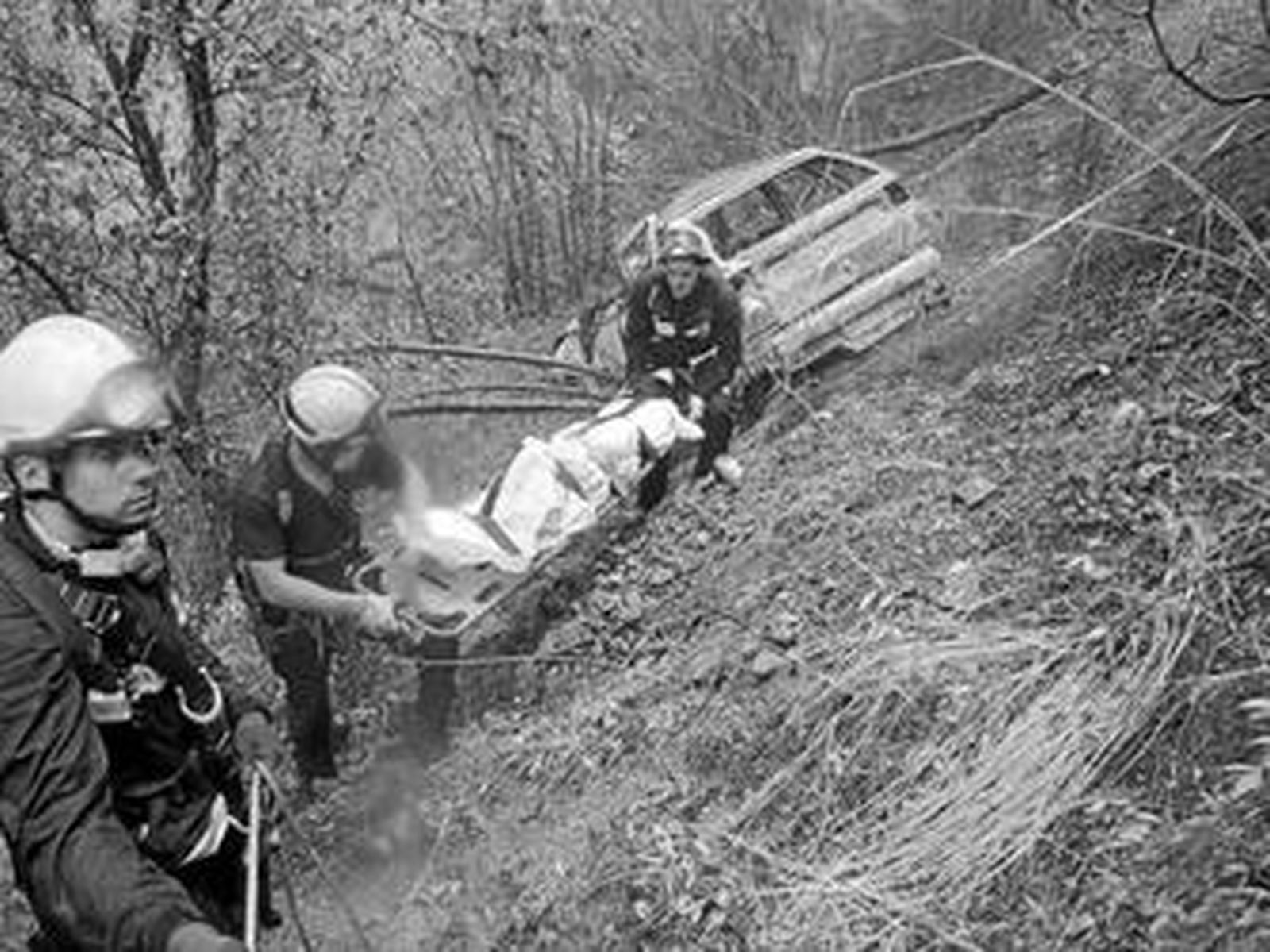 Varios bomberos, ayer, rescatan el cuerpo de la víctima del accidente.