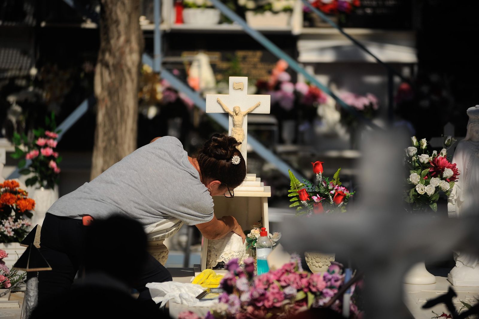Una mujer limpia y repara los ornamentos de una sepultura, ayer, en el Cementerio de San Juan, en El Palo.