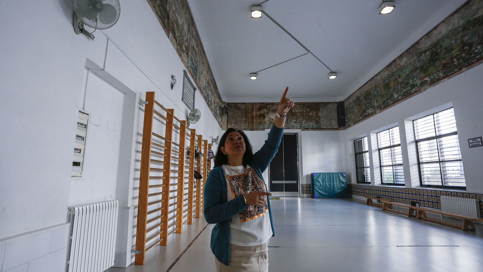 La directora señala las pinturas murales del actual gimnasio.