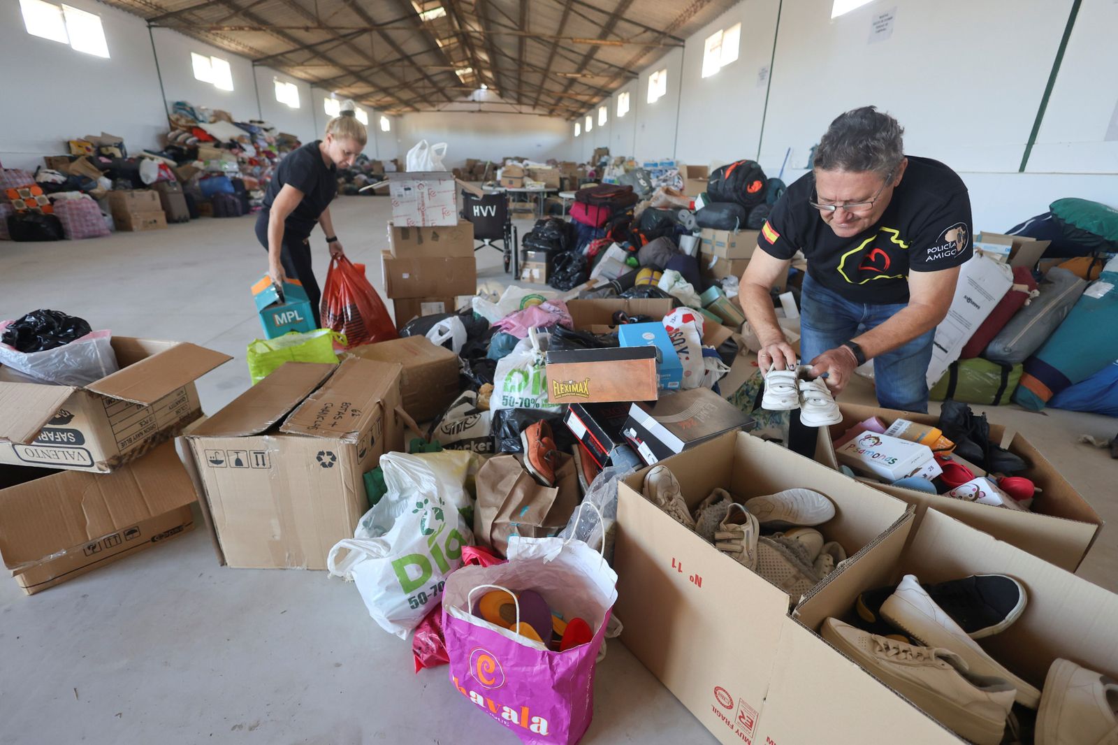 Voluntarios en la nave cedida por Famadesa clasifican las donaciones.