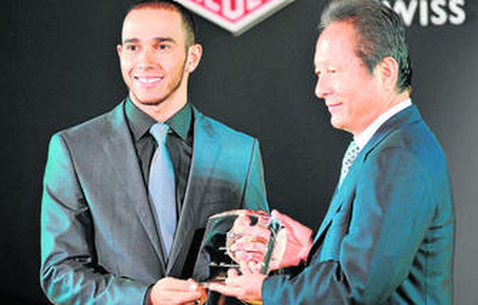 El ex piloto japonés Masanori Sekiya entrega un premio a Lewis Hamilton.