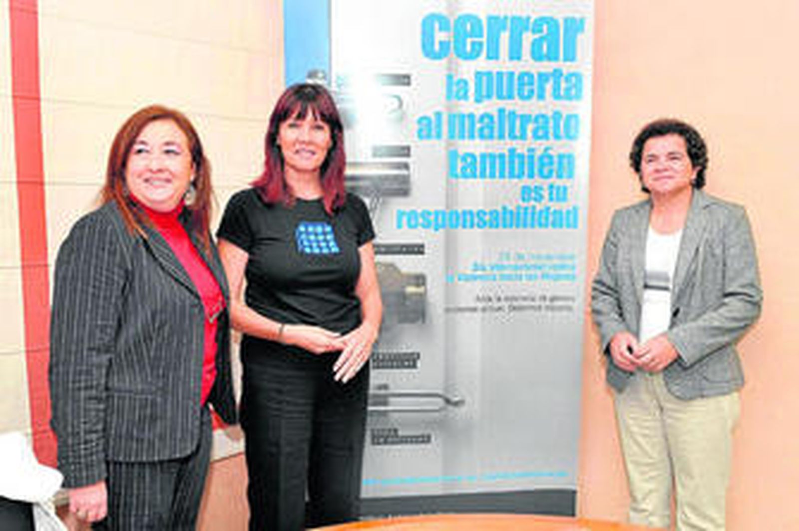 Navarro posa ante el cártel de la campaña contra la violencia de género junto a Soledad Pérez y Soledad Ruiz.