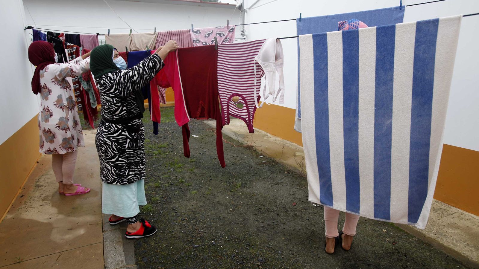 Mujeres temporeras tienden la colada en sus viviendas en una finca onubense