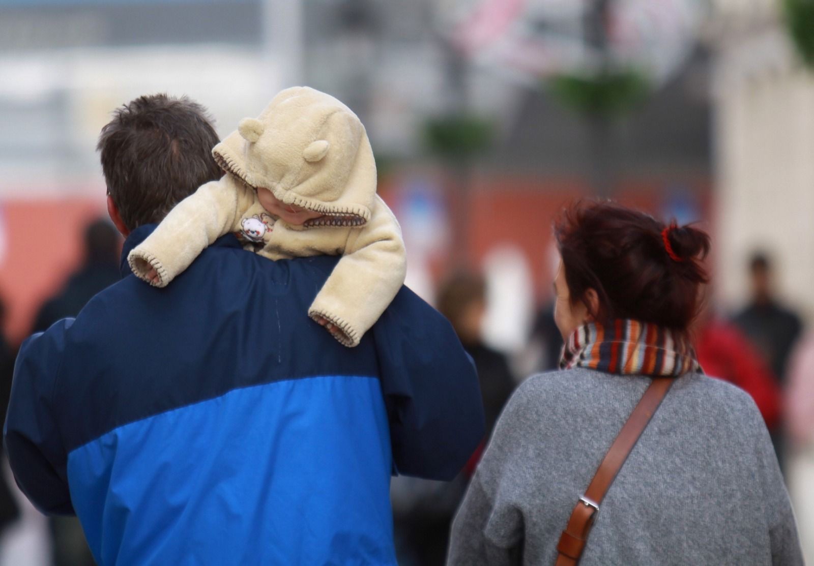 Una pareja con un niño pasean abrigados.