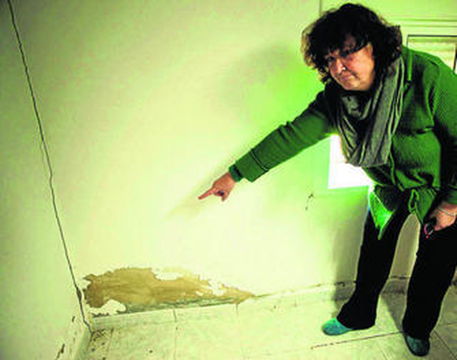 Una vecina del barrio de Las Peñas muestra la grieta aparecida en su vivienda.