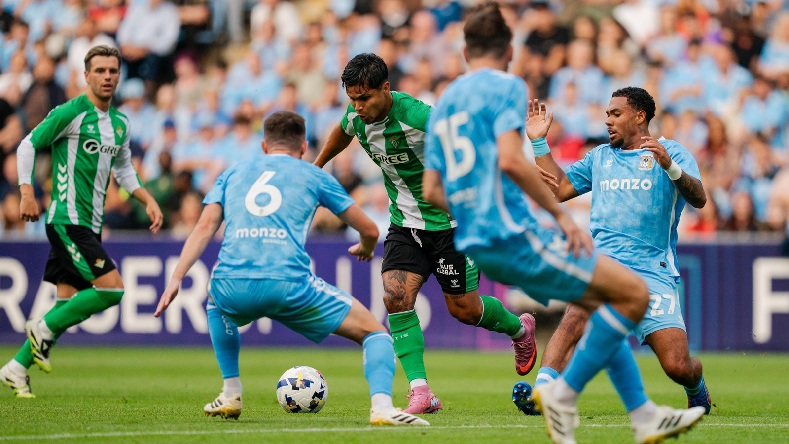 El colombiano Cucho Hernández conduce el balón rodeado de varios rivales del Coventry ante la mirada de Lo Celso.