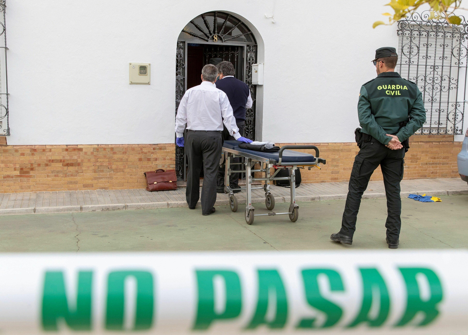Miembros de los servicios funerarios se dirigen a la vivienda de la localidad sevillana de Aznalcóllar donde esta tarde ha sido encontrado el cuerpo sin vida de una mujer de 80 años con indicios de violencia.