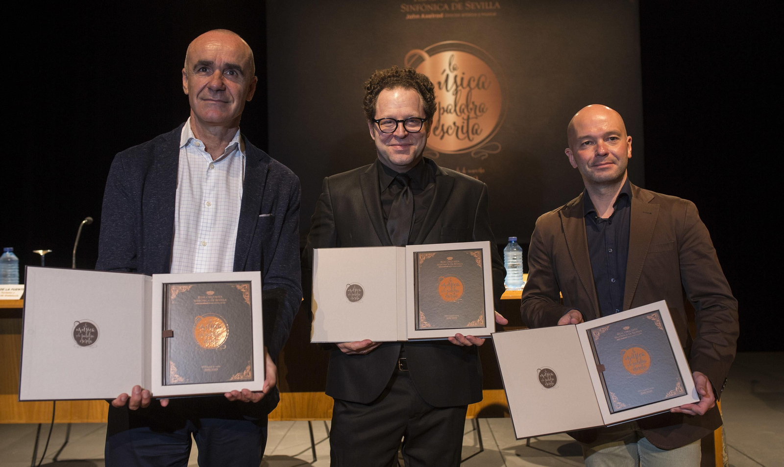 Antonio Muñoz, John Axelrod y el delegado José Manuel Girela, con el libro de la programación.