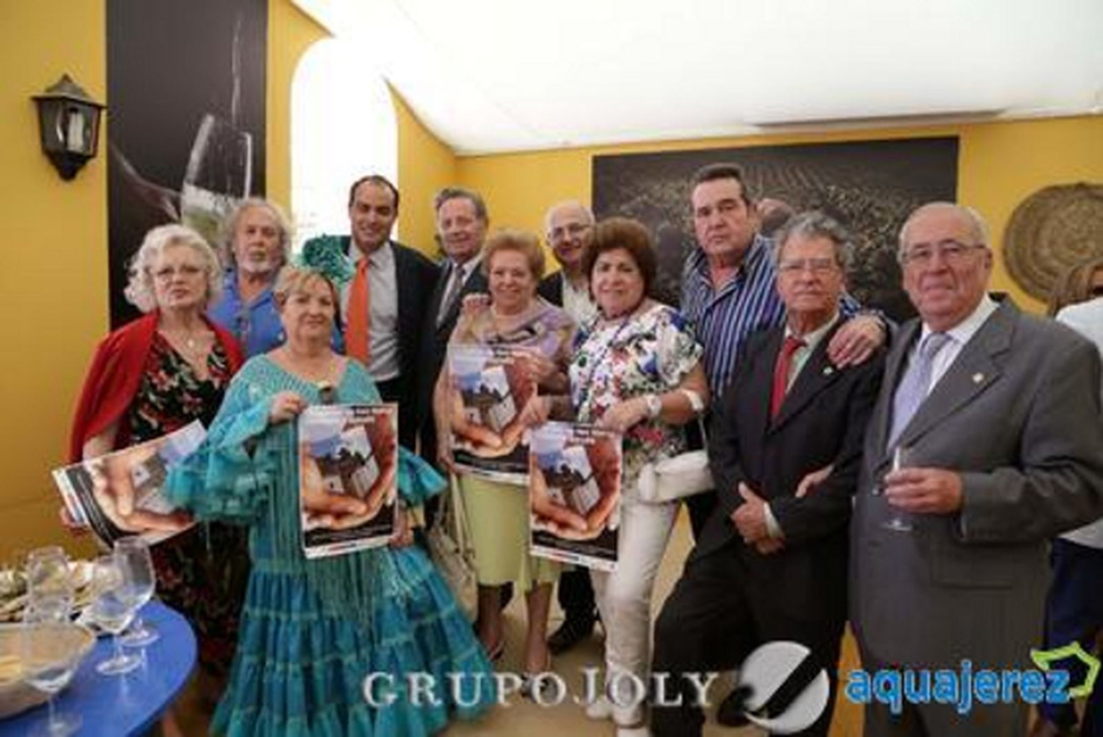 David Fernández, al fondo, posa en la caseta del Diario junto al párroco Antonio López Fernández y una parte de los integrantes de la plataforma ‘Jerez por San Mateo’ y Paleta de Colores.

Foto: Manuel Aranda