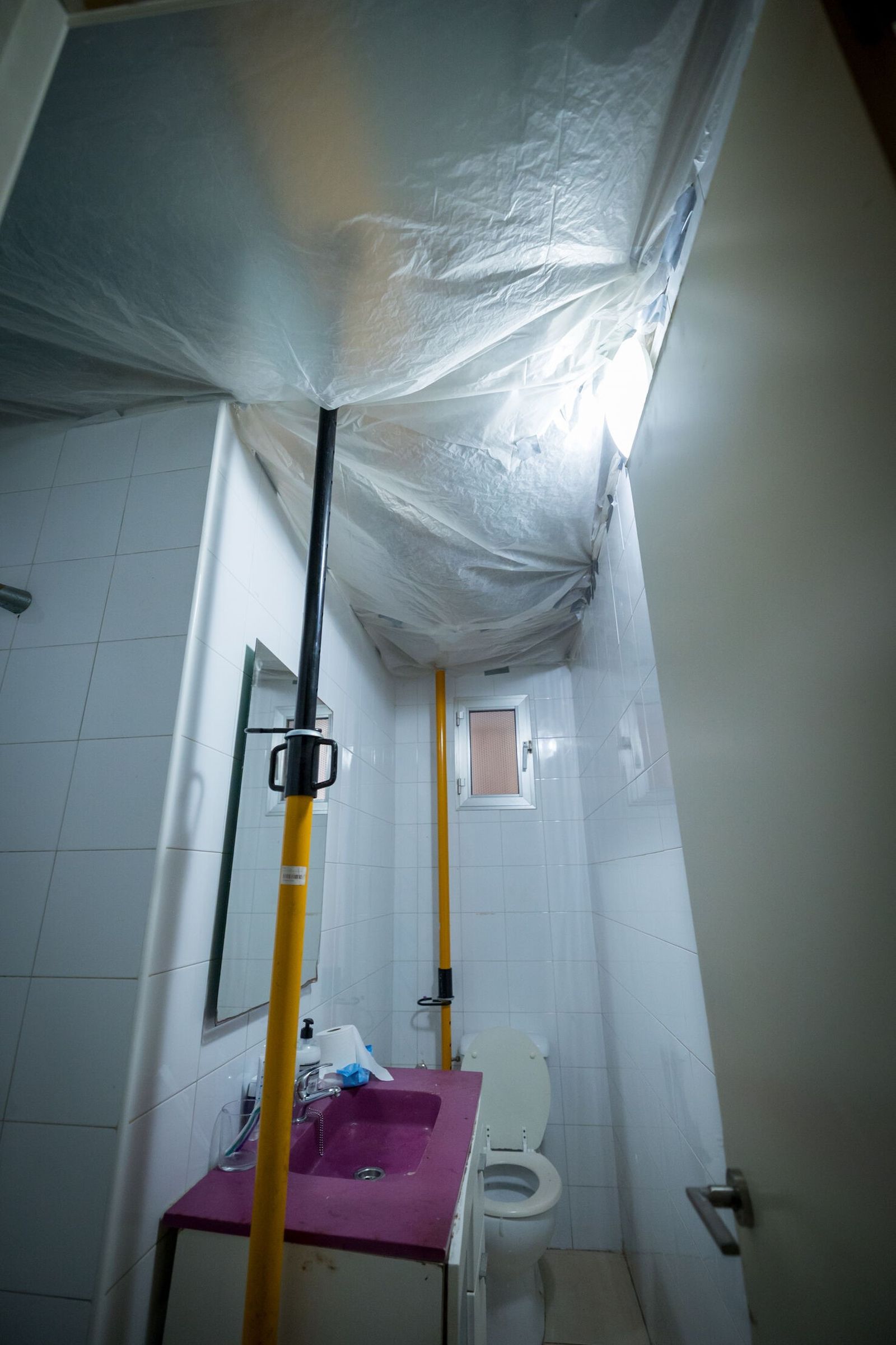 Un cuarto de baño con el techo abierto y tan solo cubierto con un plástico.