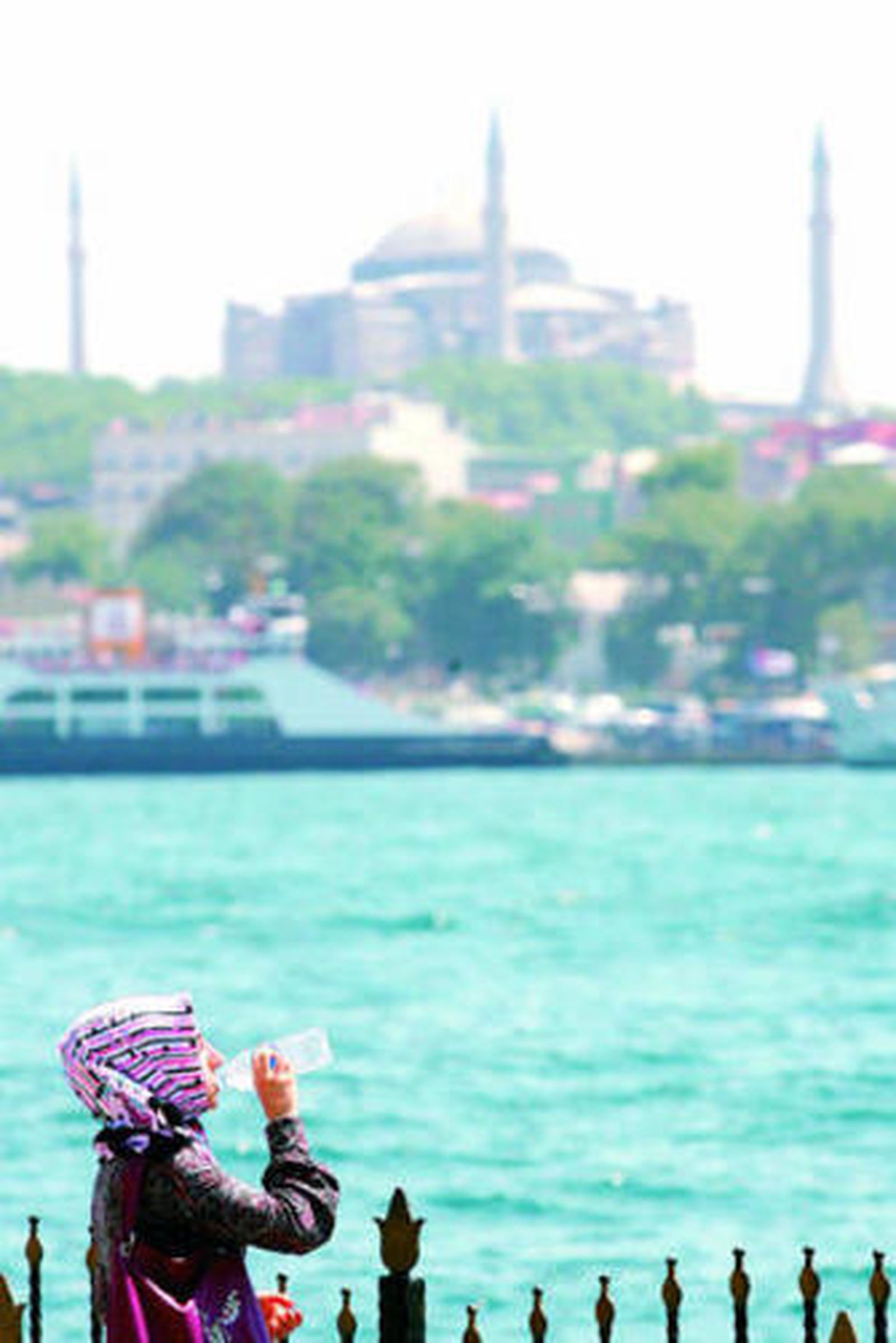Una mujer bebe agua y pasea por Estambul.