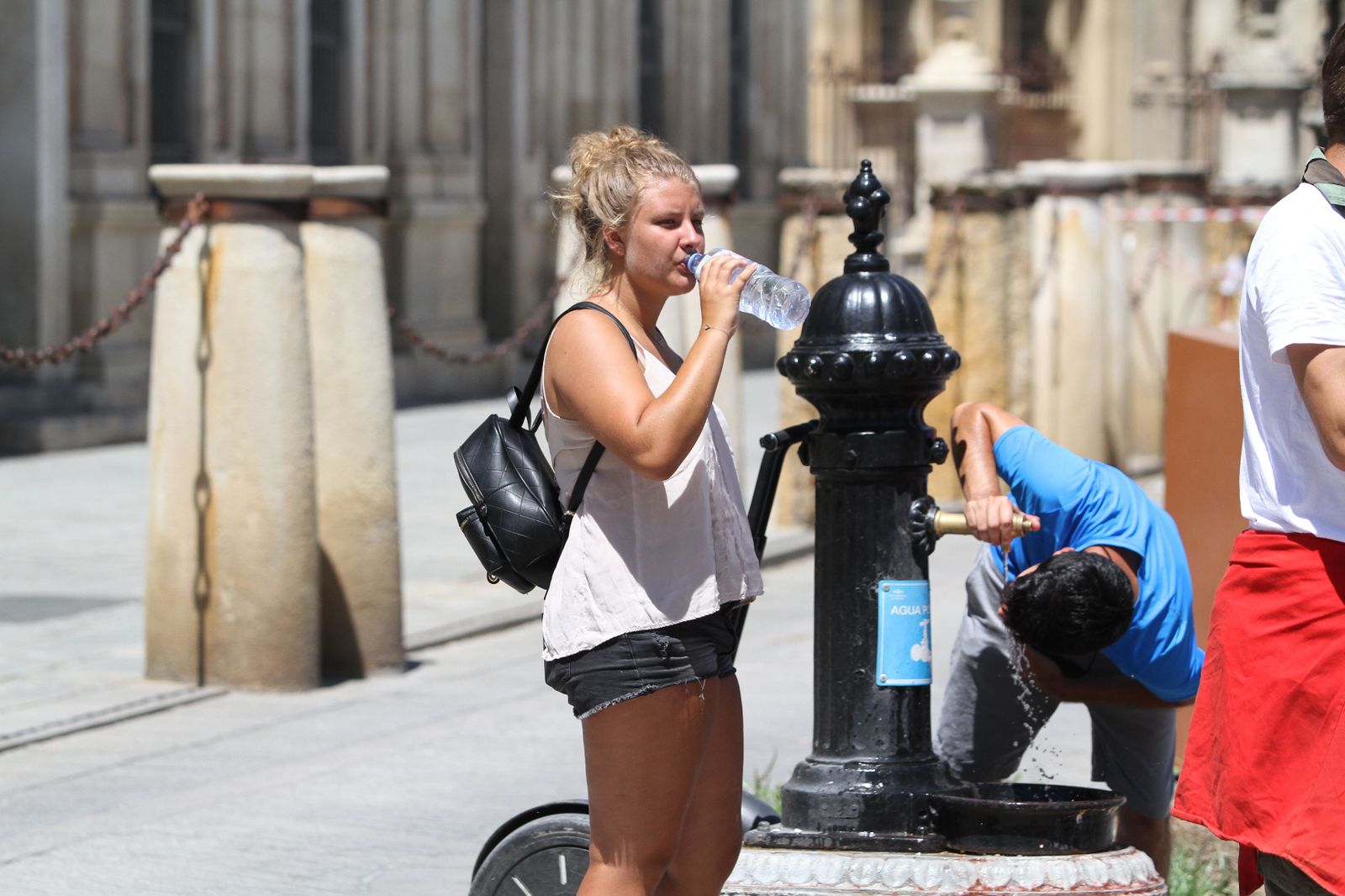 Varios turistas beben en las fuentes instaladas en la zona monumental de Sevilla.