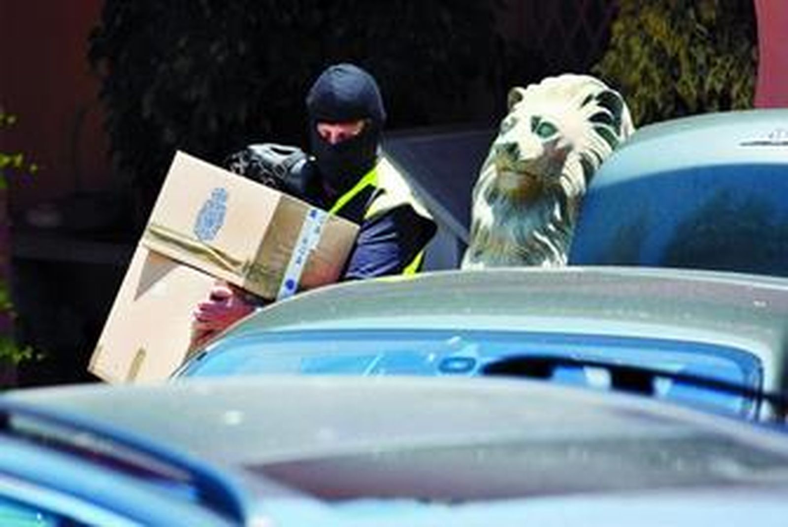 Un policía saca material intervenido en el registro de una mansión en una urbanización marbellí.