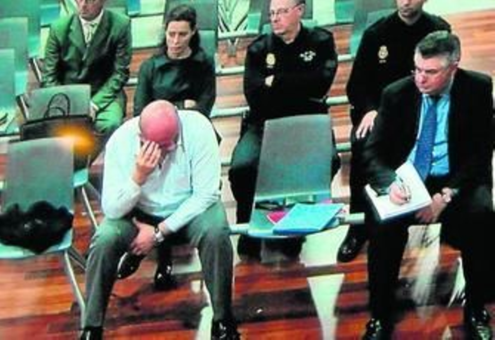 Juan Antonio Roca, custodiado por la Policía, en el banquillo junto a otros procesados a finales de marzo de este año.