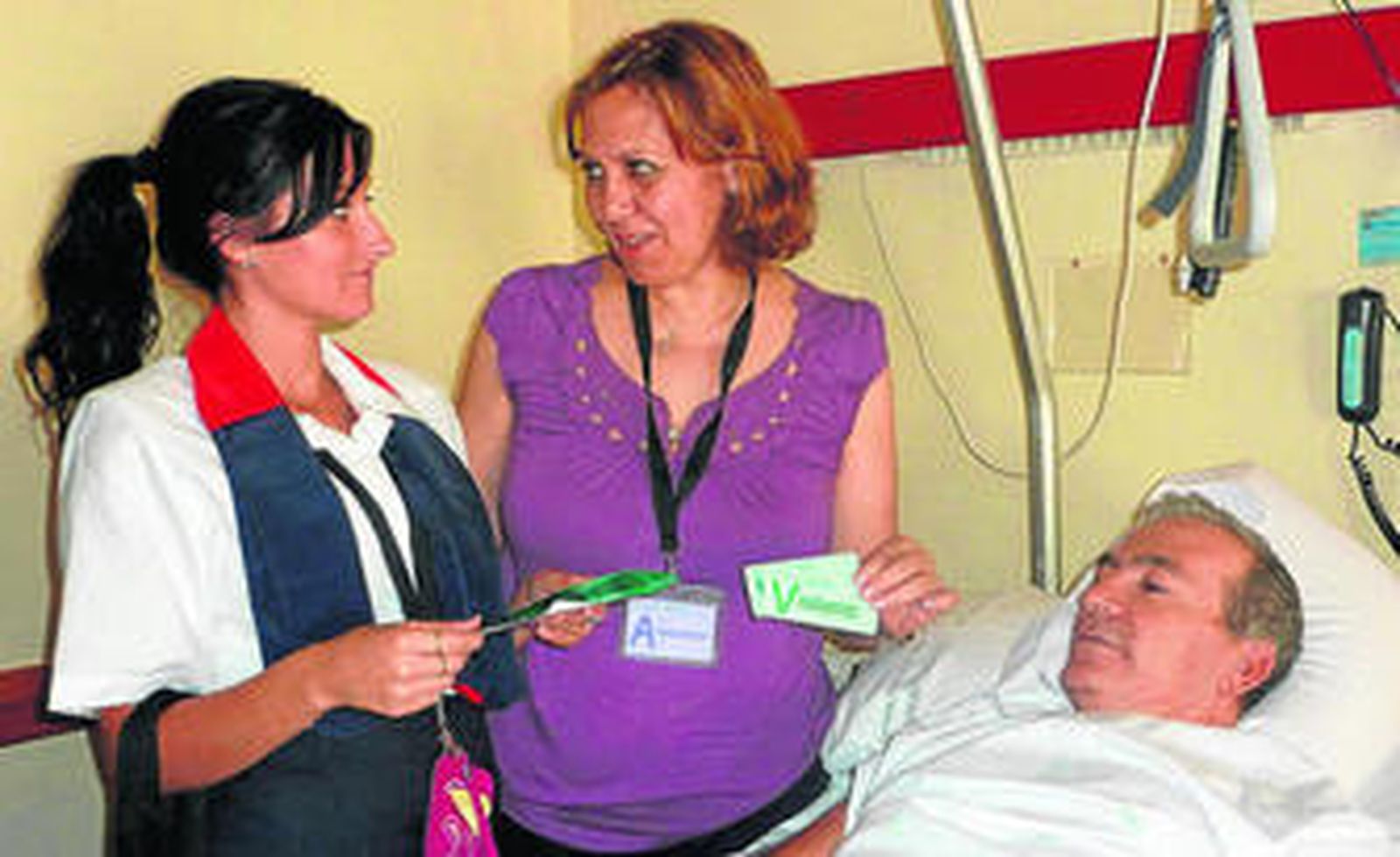 Una auxiliar de información entrega las tarjetas de visita a una acompañante.