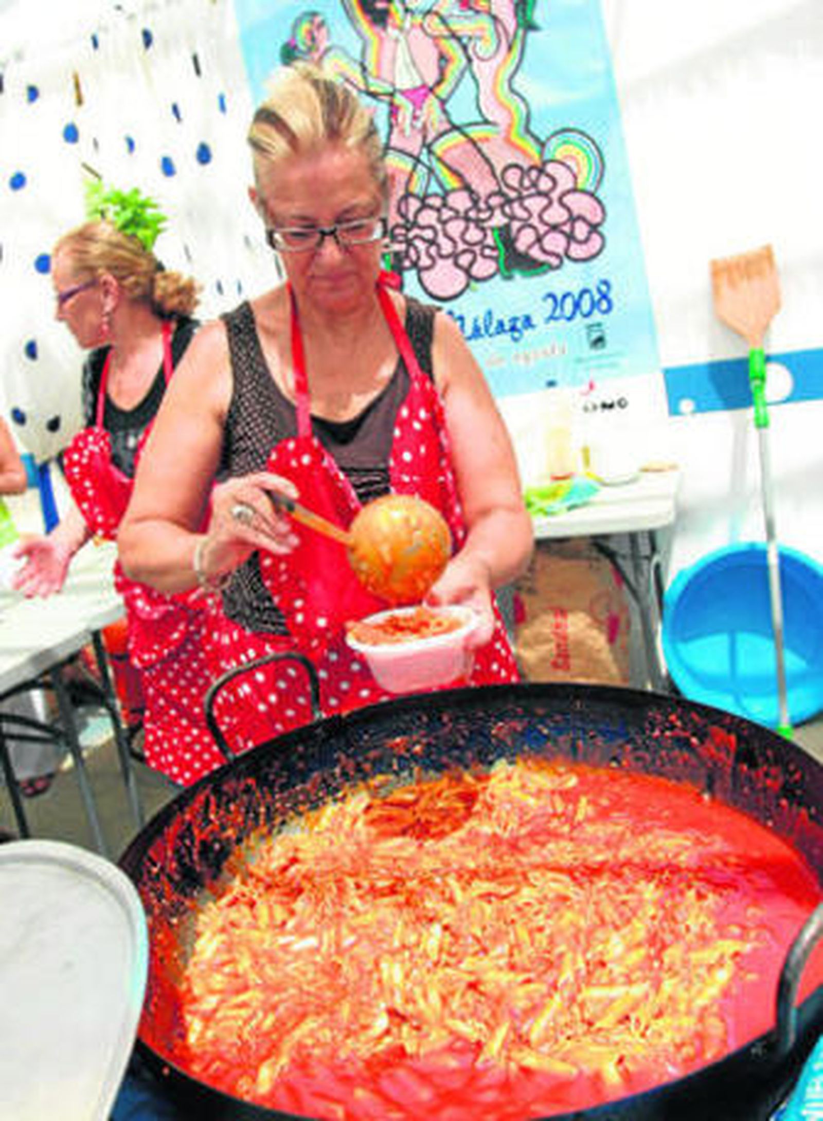 Una señora sirve macarrones en la feria de Málaga.