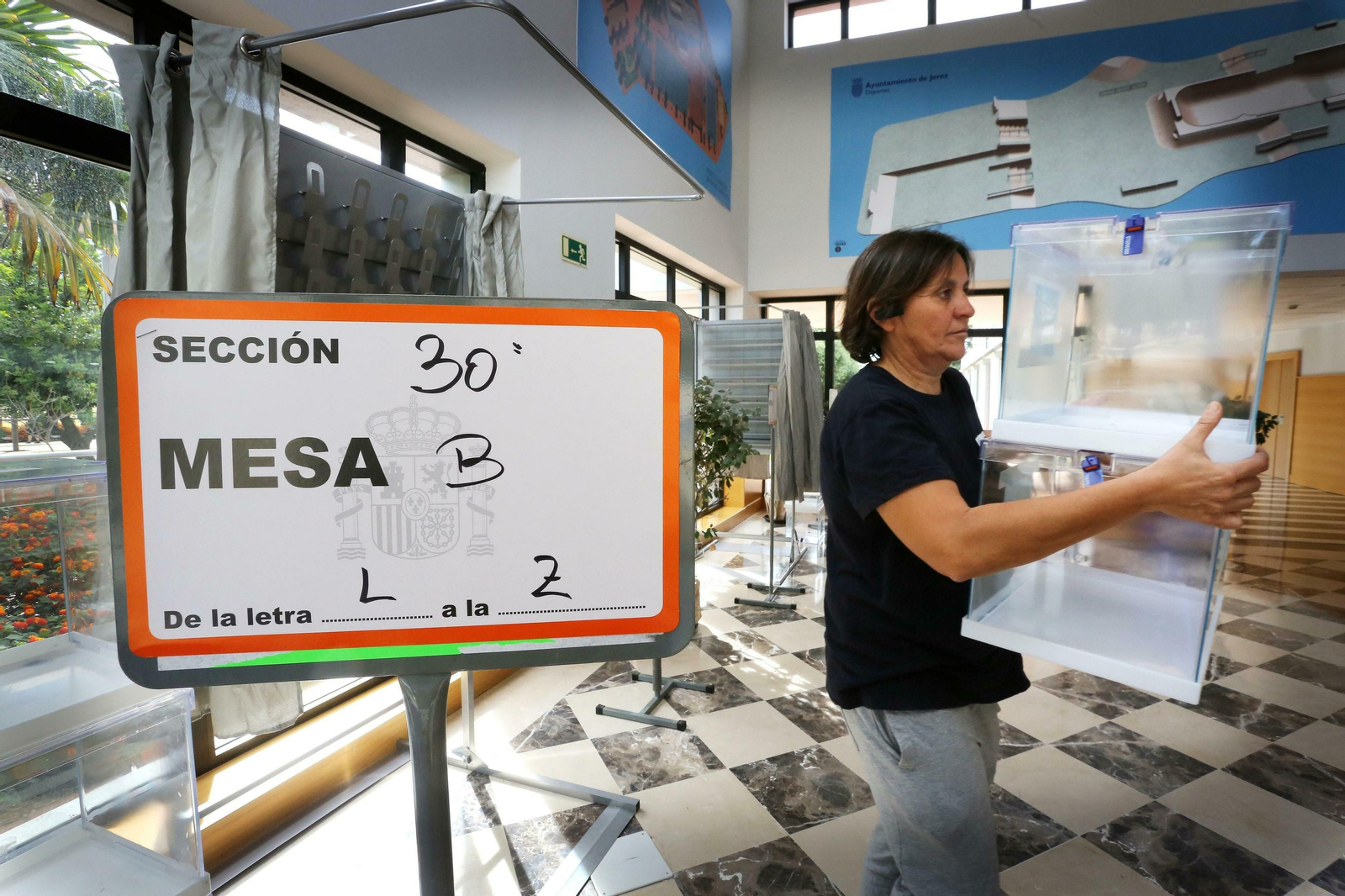 Una empleada municipal instala las urnas en la mesa del complejo deportivo de Chapín.