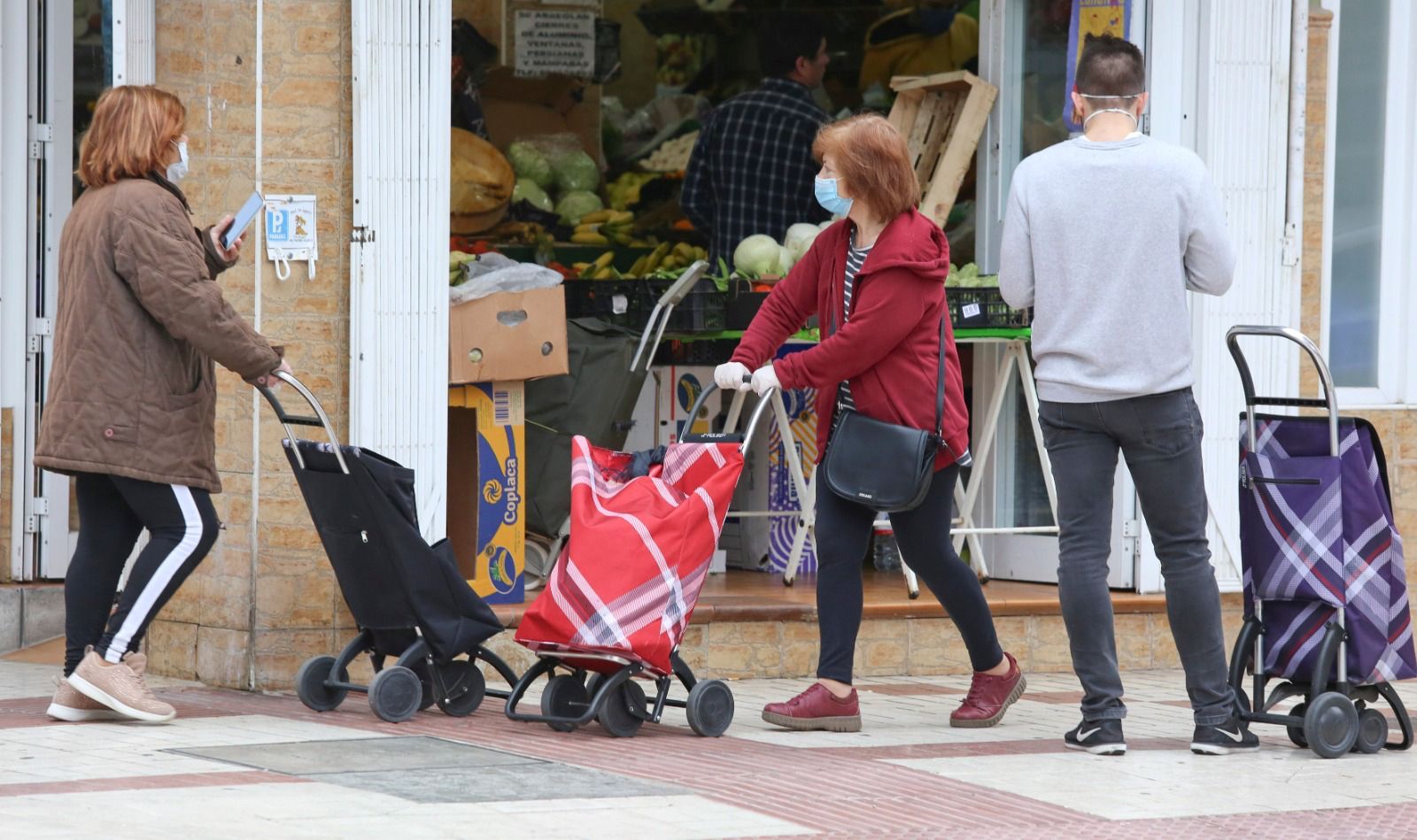 Varios clientes aguardan su turno a las puertas de una frutería.