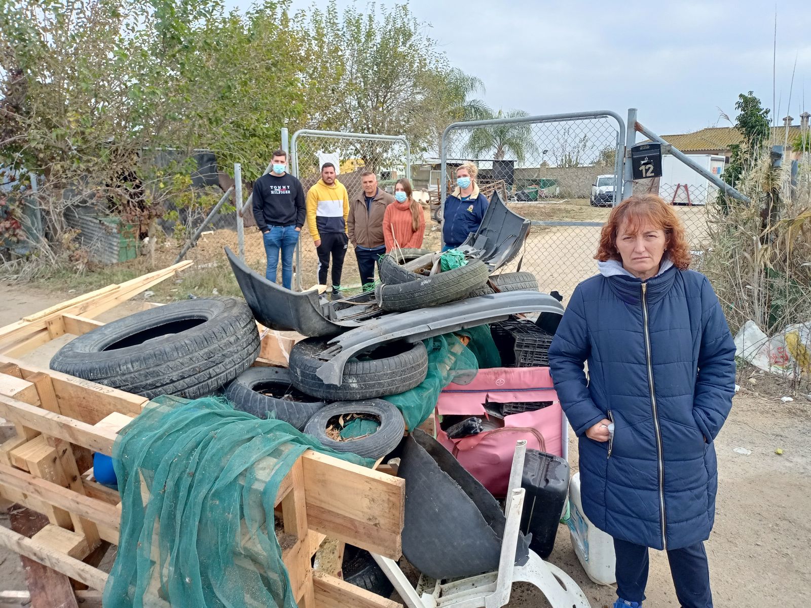 Rocío Becerra y su familia, junto a uno de los montones de residuos que cortan el acceso a su vivienda en señal de protesta.