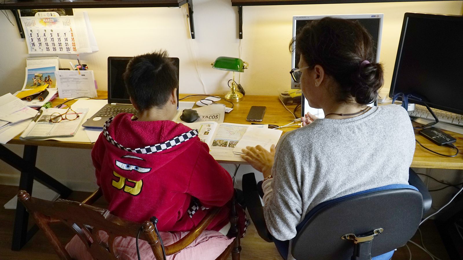 Una madre ayuda a un menor con sus deberes.