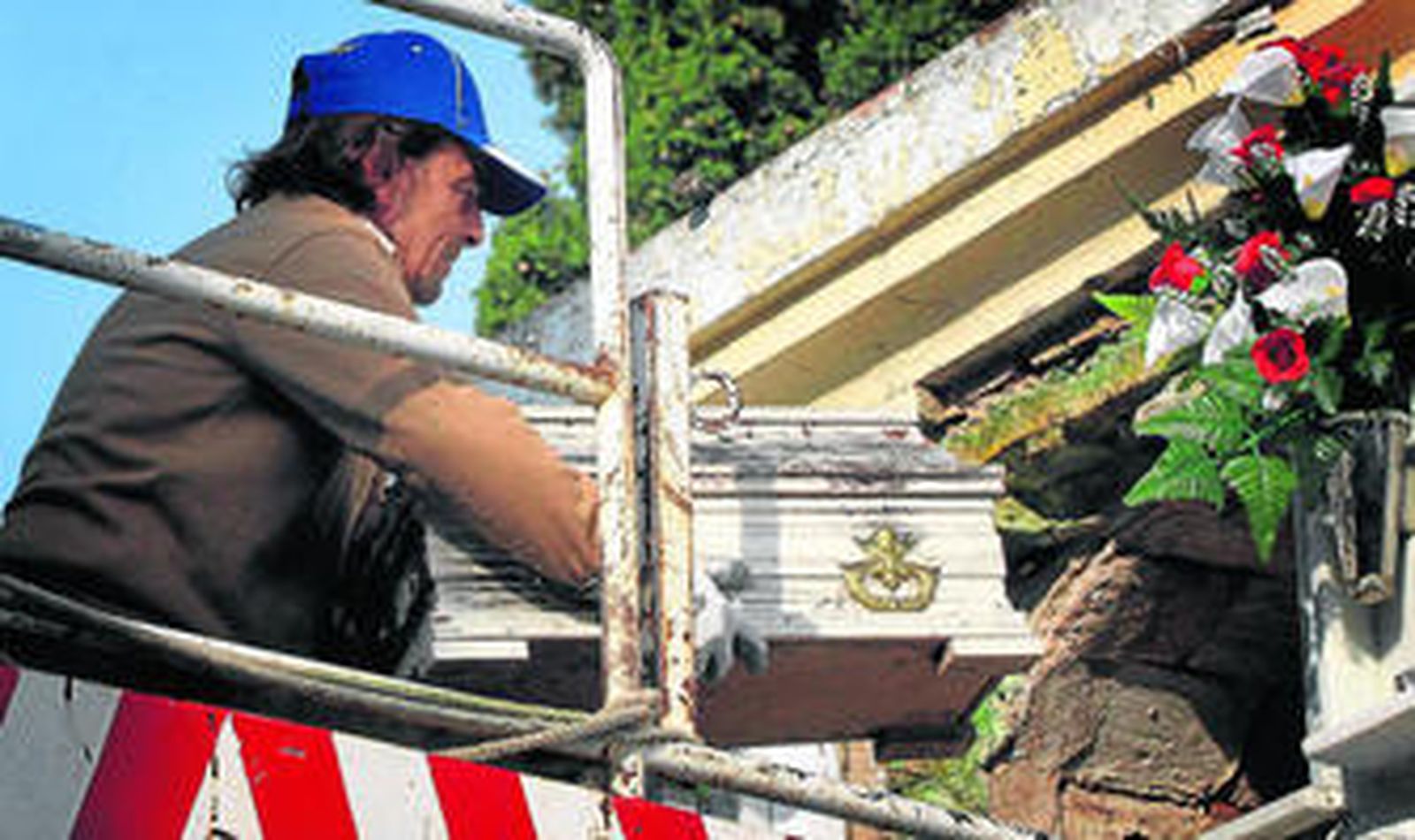 Momento en que un operario extrae del nicho ayer el féretro del bebé.