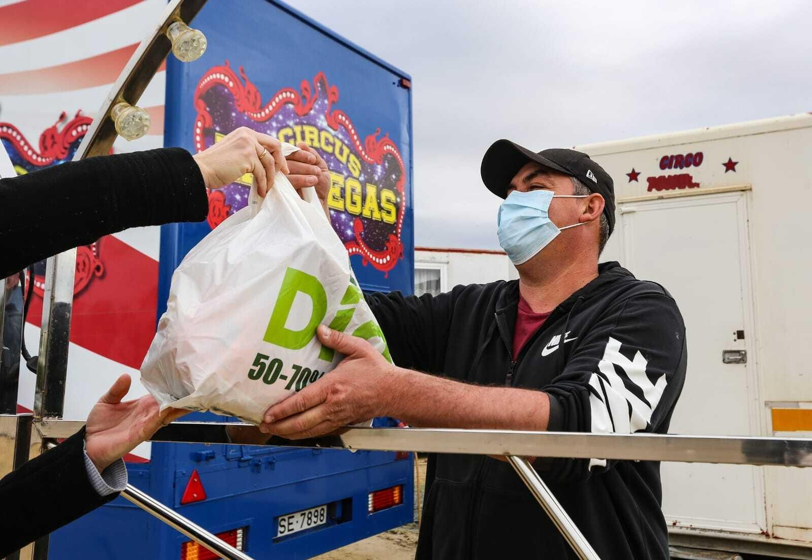 Una vecina entrega una compra a las familias del circo acampado en La Magdalena.