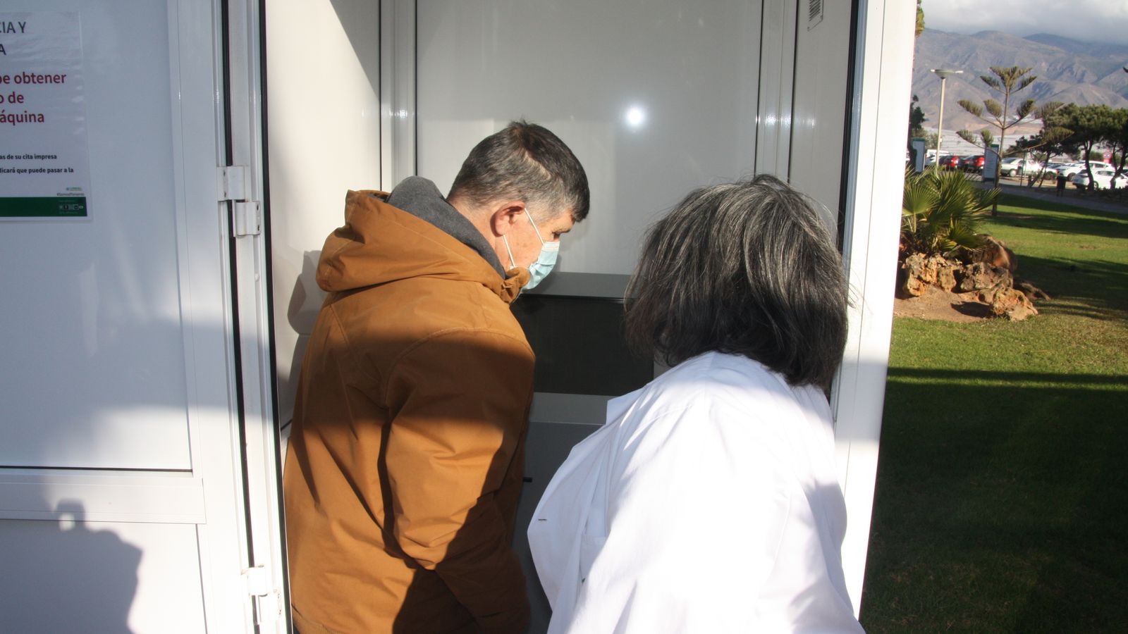 Una profesional del hospital asesora a un usuario en la dispensación del ticket.