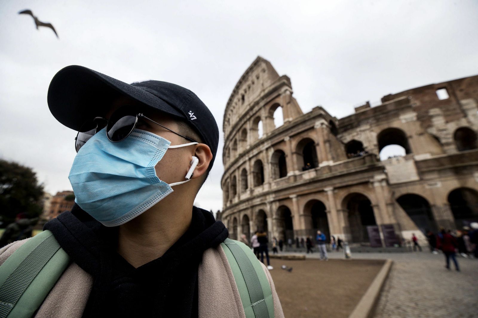 Un turista con una máscara protectora ante el Coliseo romano.