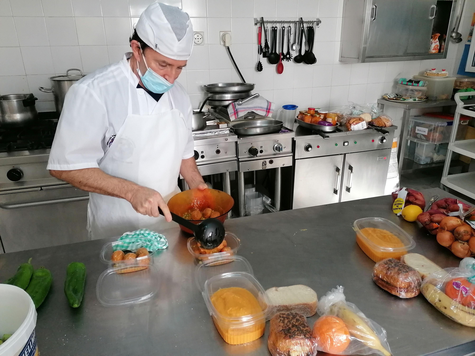 Uno de los cocineros prepara una barqueta con comida.