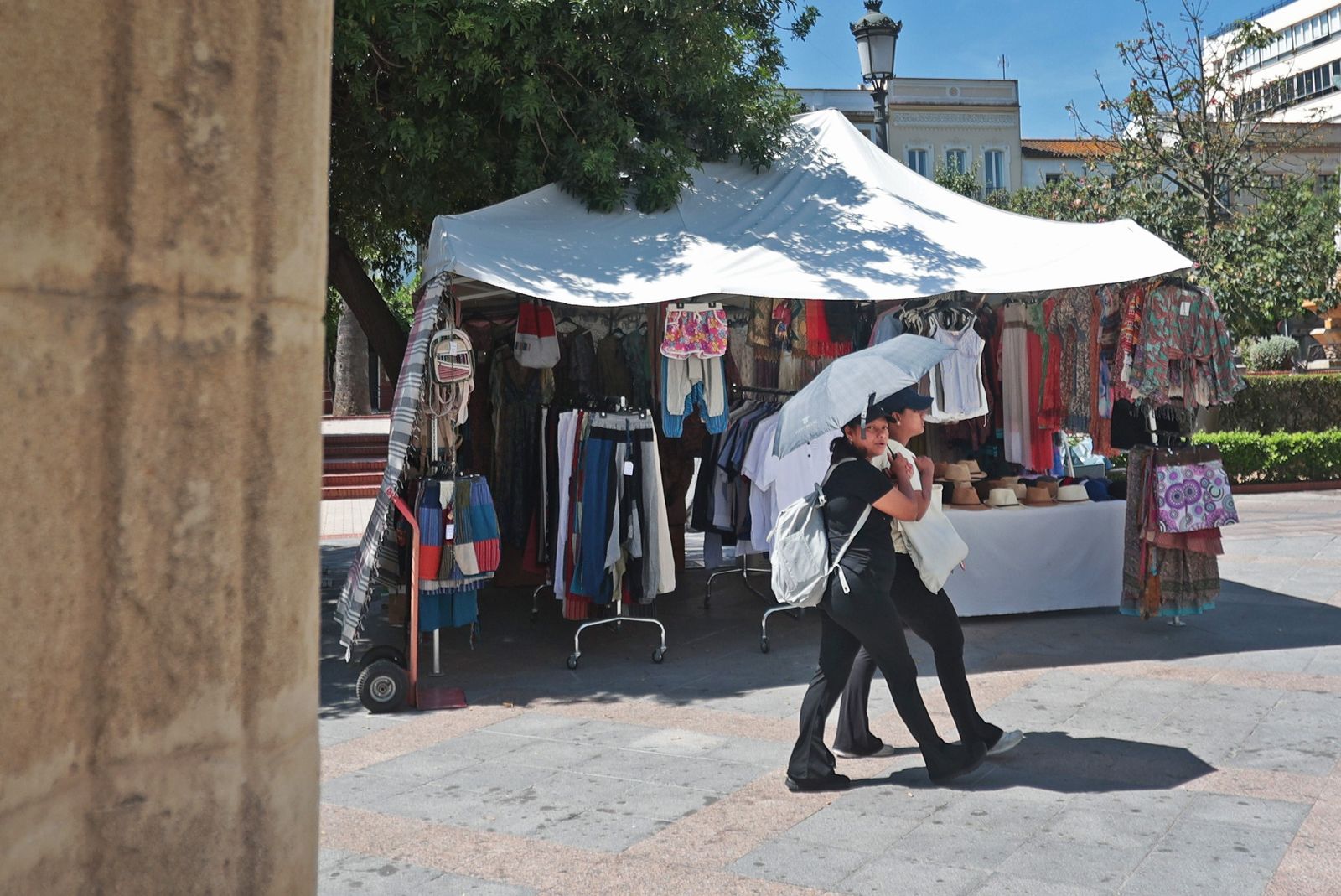 Dos personas se protegen de los rayos de sol mientras caminan por la plaza de las Angustias de Jerez